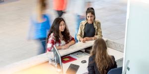 Two students at the Welcome Centre desk speaking with a staff member